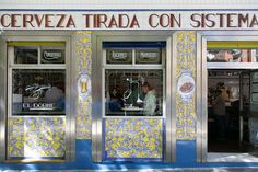 two men are standing in the window of a restaurant that has yellow and blue tiles on it