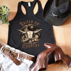 Show your inner cowgirl in this cute country cow skull tank. A great tank top while rockin' out at your favorite country concert. An awesome gift for your best friend or favorite country girl. All of our tank tops are printed on the Next Level 1533 racerback tank. This racerback cut looks good on any woman's shoulders. It's soft and comfortable and is made from 60% combed ring-spun cotton, 40% polyester. The fabric has a subtle luxurious feel, making it pleasant to touch. Made from specially spu Western Tops For Country Concerts In Summer, Western Style Tops For Country Concerts And Festivals, Western Cotton Tops For Country Festivals, Western Style Tops For Summer Western Events, Black Western Style Tops For Summer, Fitted Sleeveless Top For Rodeo, Fitted Tops For Summer Country Concerts, Fitted Country Style Tops For Country Events, Black Western Tops For Summer