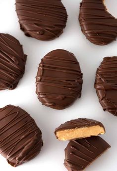 chocolate covered cookies with peanut butter in the middle on a white surface, ready to be eaten