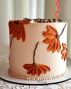 a white cake with orange flowers on it and a red candle sticking out of the top