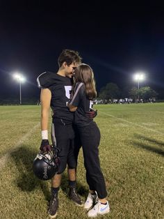 a man and woman standing on top of a lush green field next to each other