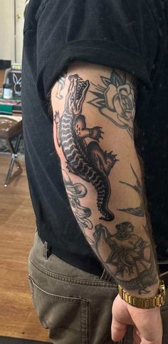 a man with a dragon tattoo on his arm is pointing to the left side of his arm