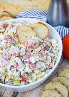 a white bowl filled with salad next to sliced bread