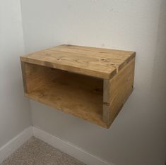 a wooden shelf sitting on the side of a wall next to a carpeted floor