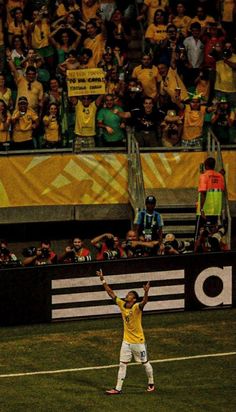 a soccer player holding his arms up in the air while standing on top of a field