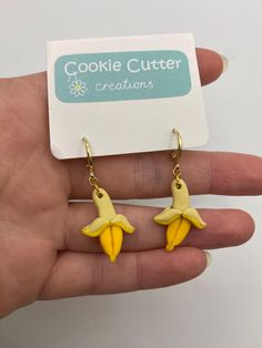 a hand holding a pair of yellow banana earrings