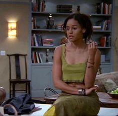 a woman sitting on top of a table in a living room next to a book shelf