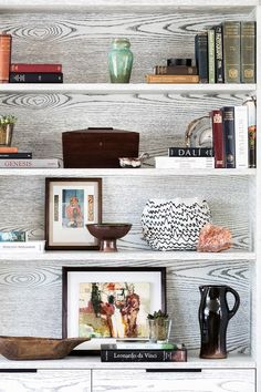 a white book shelf with books and vases on it