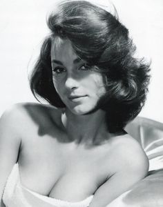 black and white photograph of a woman with no shirt on laying in bed wearing a towel