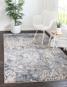 a white chair sitting on top of a wooden floor next to a rug and potted plant