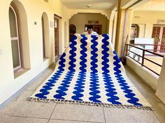 a large blue and white blanket sitting on the ground in front of a hallway with arched windows