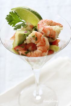 shrimp and avocado salad in a martini glass with lime wedges on the side