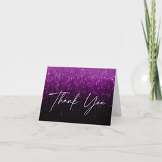 a thank you card sitting on top of a table next to a vase with flowers