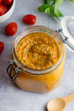 a jar filled with yellow sauce next to tomatoes