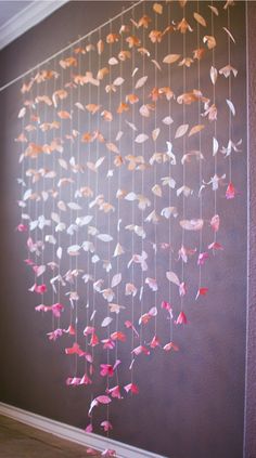 some pink and orange paper butterflies hanging from the ceiling in front of a brown wall