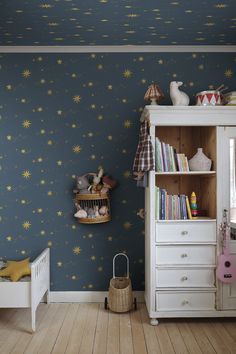 a child's room with stars painted on the wall and wooden flooring, along with a white dresser