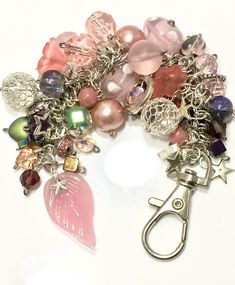 a close up of a bunch of beads and charms on a white surface with a pair of scissors