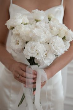 a bride holding a bouquet of white flowers