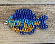 a blue and yellow beaded fish on a wooden surface