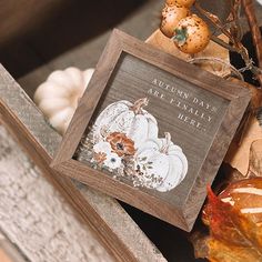 a wooden frame with some pumpkins and leaves on it next to other autumn decorations