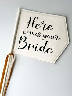 here comes your bride sign hanging on the wall next to some clothes pins and a pair of scissors