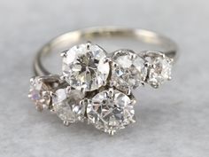 an antique diamond cluster ring with three old cut diamonds in the center, on a gray background