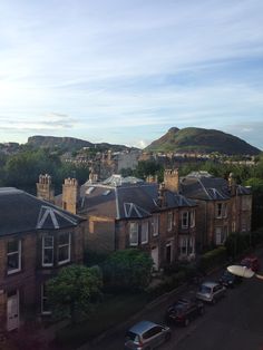 an aerial view of some houses and mountains in the distance with cars parked on the street