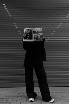 a person standing on the sidewalk holding up a magazine