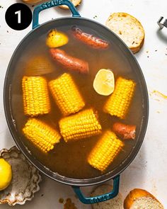 corn on the cob in a pot with lemons and bread