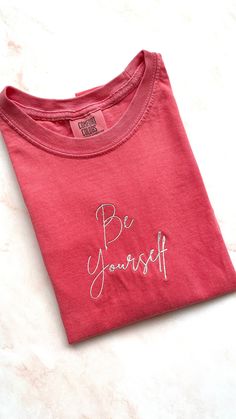 Embroidered pink colored t-shirt with phrase "Be Yourself" in white Each item is made to order so slight variations may occur Pink T Shirt, Pink Tshirt, Be Yourself, Comfort Colors, Sweat Shirt, Gender Neutral, Bathing Beauties, Adult Outfits, Electronic Accessories