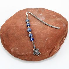 a beaded necklace on a rock with a silver turtle charm hanging from it's end