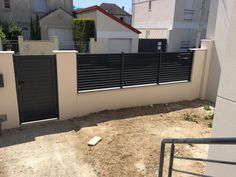 a gated in area next to a building with two doors and a fence on the other side