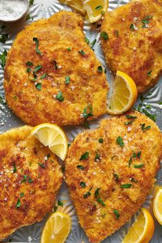 four chicken patties with lemons and parsley on a silver platter, ready to be eaten