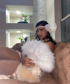 a woman sitting on top of a couch holding a fluffy white fan in her hand