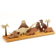 an image of dinosaurs in the wild on a wooden base with palm trees and mountains