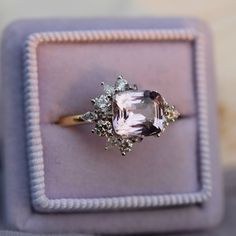 an engagement ring is displayed in a purple box with white trimmings on it