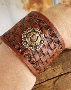 This gorgeous leather cuff bracelet is basket stamped with a beautiful horse shoe concho added.  The cuff is 2" wide and snaps closed fitting up to an 8 inch wrist. If you have a small wrist and would like us to add an additional snap, please let us know. Vintage Hand-tooled Leather Cuff Bracelet, Vintage Leather Bracelet With Concho, Rustic Brown Bracelet With Concho, Rustic Brown Concho Bracelets, Vintage Brown Jewelry For Rodeo, Hand Tooled Brown Cuff Jewelry, Hand Tooled Brown Jewelry For Rodeo, Brown Hand Tooled Jewelry For Rodeo, Vintage Adjustable Leather Bracelet With Concho