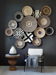 a chair and table in front of a wall with baskets hanging on it's side