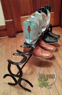 four pairs of shoes are stacked on a rack in front of a door with wooden floors