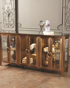 an ornately decorated sideboard with glass doors and gold trimmings in a room