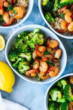 four bowls filled with shrimp, broccoli and rice next to lemon wedges