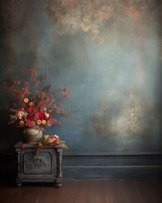 a vase filled with flowers sitting on top of a wooden floor next to a wall