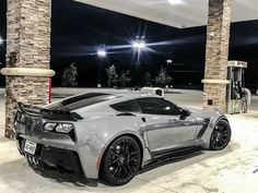 a silver sports car parked in front of a gas station with its lights on at night