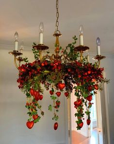 a chandelier decorated with red flowers and greenery