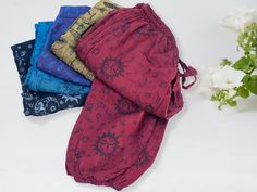 "Discover our vibrant Hippie Trousers, lovingly handcrafted by skilled artisans in Nepal, bringing your bohemian and hippie style dreams to life. 🌟 PRODUCT DETAILS: - Lovingly Handcrafted in Nepal - 100% Cotton - One Size Fits All: for all-day comfort - Adjustable drawstring waist for versatile sizing - Elasticated ankles -  Spacious side pockets, perfect for carrying your essentials, along with a single rear pocket for added functionality. - Unisex - Available in two captivating prints: Celestial with suns, moons, and stars, and Mushrooms for woodland vibes 🌈 APPROXIMATE MEASUREMENTS: Waist: 25\" (stretches up to 36\") Full Length: 41\" Our trousers are ONE SIZE, designed to fit most body types. To make sure they're the perfect fit for you, we recommend measuring yourself using our size Handmade Cotton Bottoms For Festival, Handmade Cotton Festival Bottoms, Handmade Hippie Bottoms For Festival, Handmade Multicolor Festival Bottoms, Hippie Handmade Festival Bottoms, Hippie Style Non-stretch Festival Pants, Hippie Blue Harem Pants, Hippie Stretch Wide-leg Harem Pants, Hippie Trousers