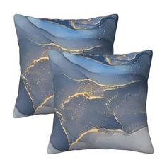 two blue and gold decorative pillows on a white background with stars in the night sky