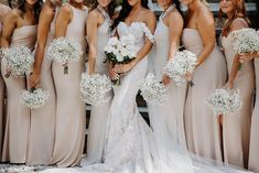 a group of women standing next to each other wearing dresses and holding bouquets in their hands