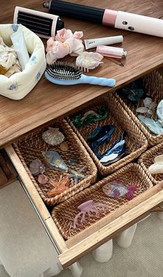 an open drawer with various items in it on a wooden table next to a brush and comb