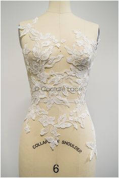 the back of a dress with white flowers and laces on it, as well as numbers