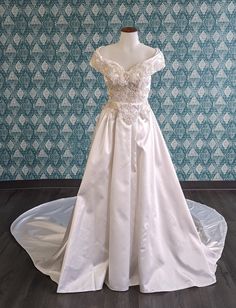 a white wedding dress on display in front of a blue wall